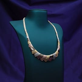 Graduated 22K gold necklace with machine-cut links on a teal bust