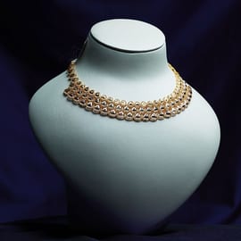 Turkish-style gold necklace with openwork filigree medallions on a white bust